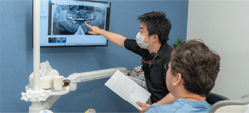口腔内の状態と治療方法の説明をしている画像